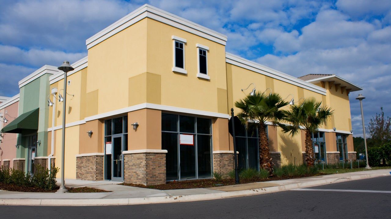 A yellow building with a sign that says ' for sale ' on it