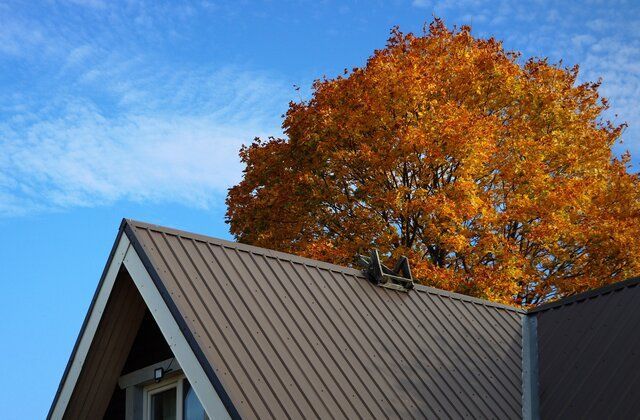 A house with a brown roof and a tree in the background.