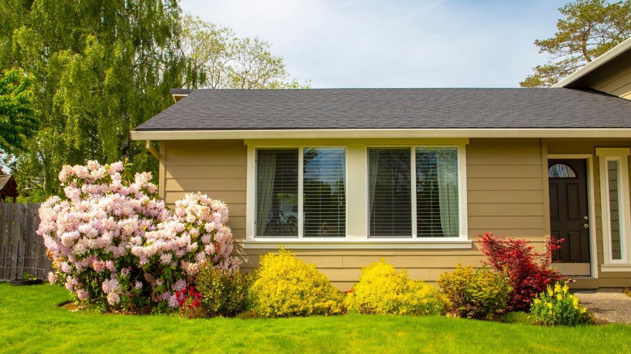 A small house with a lot of windows and flowers in front of it.