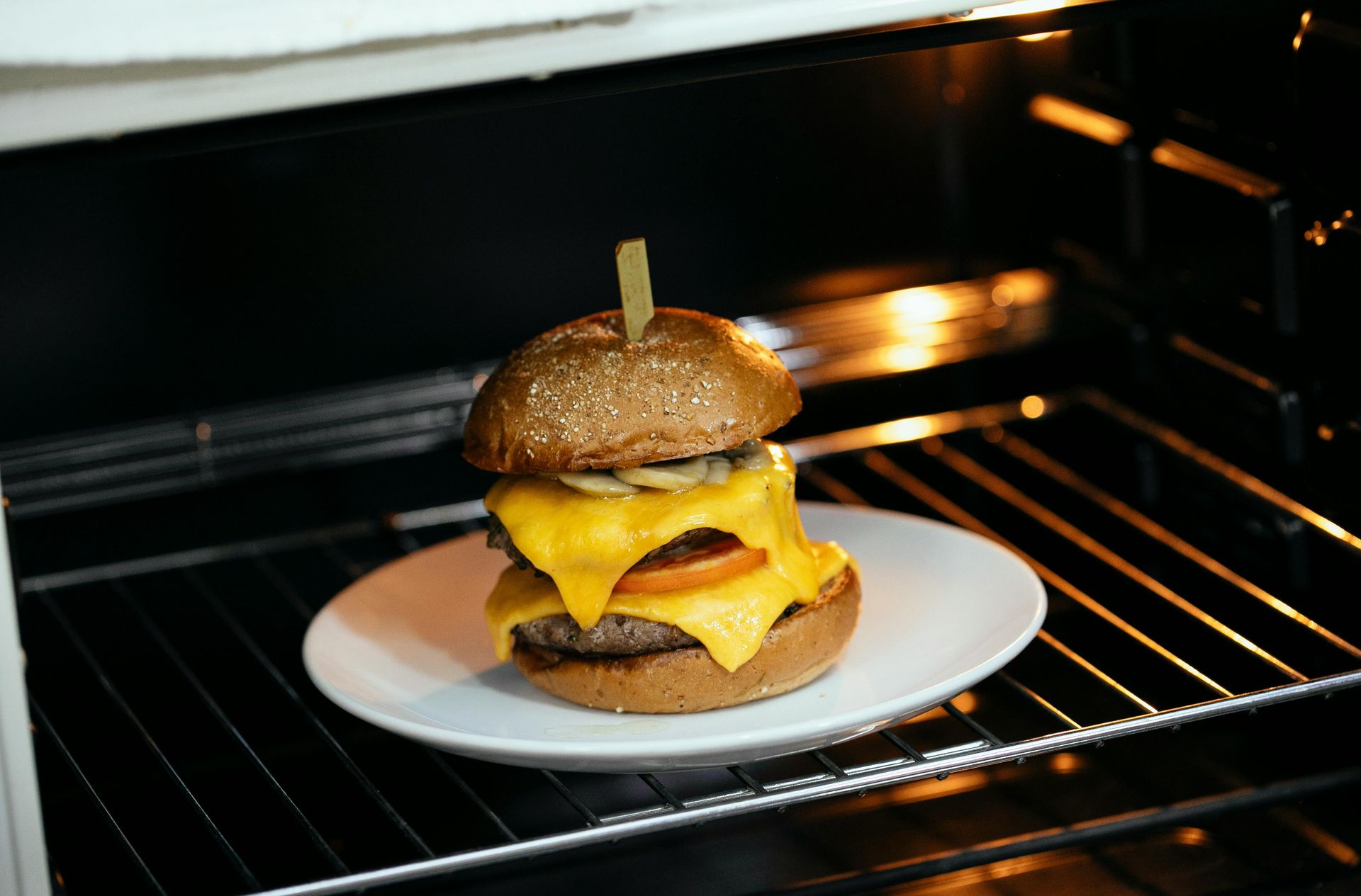 Double cheeseburger on a white plate inside an oven.