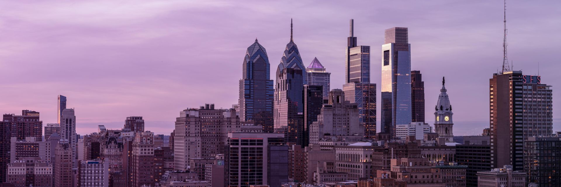 Philadelphia skyline at sunset, purple and gray hues. Skyscrapers and buildings.