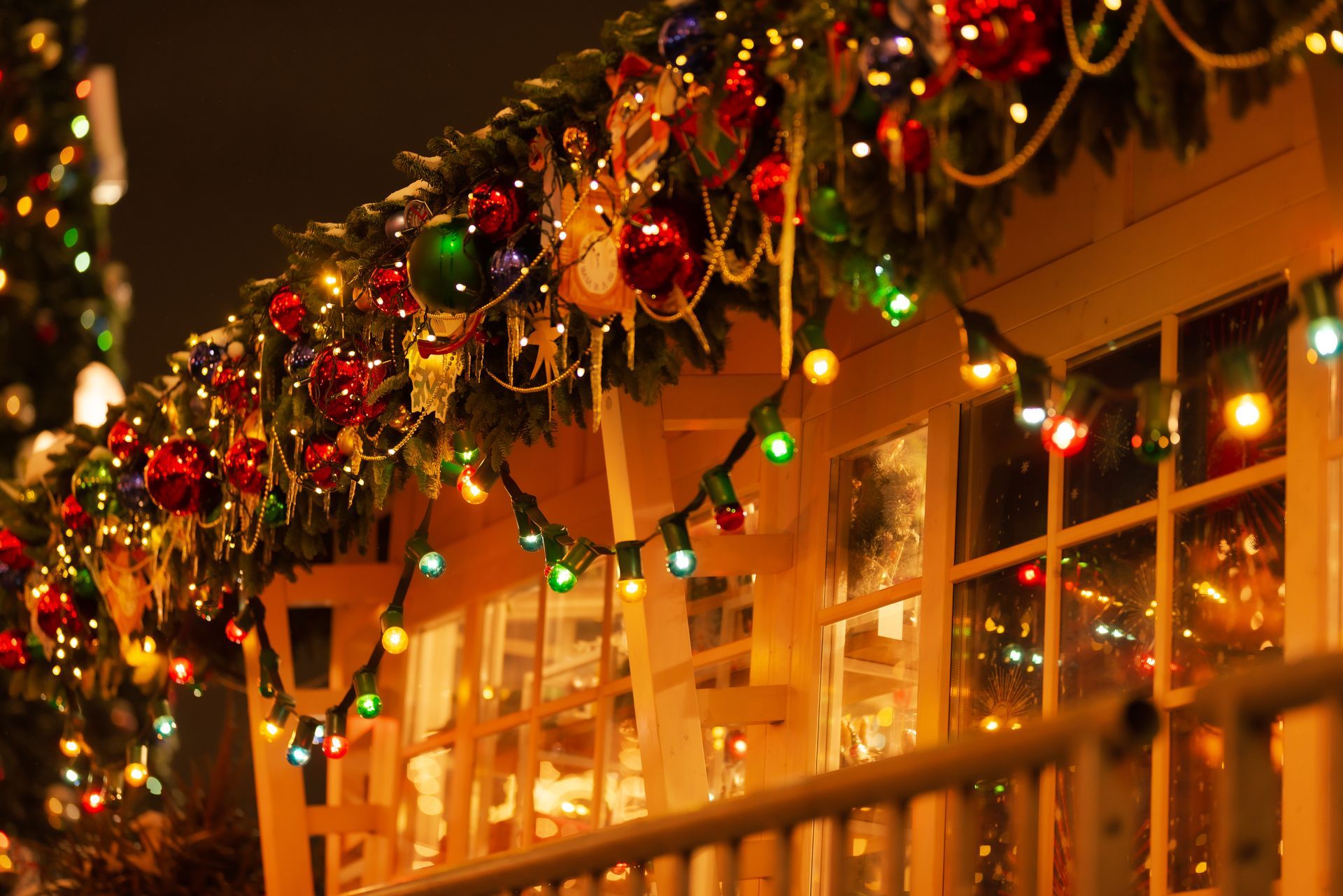 Christmas lights and ornaments decorate the eaves of a house at night.