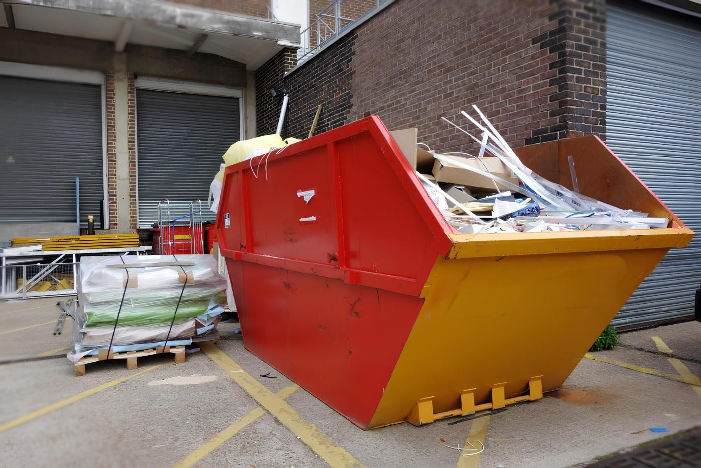 A Red and Yellow Dumpster is Sitting in Front of a Building — IBS Skip Bins in Currimundi, QLD