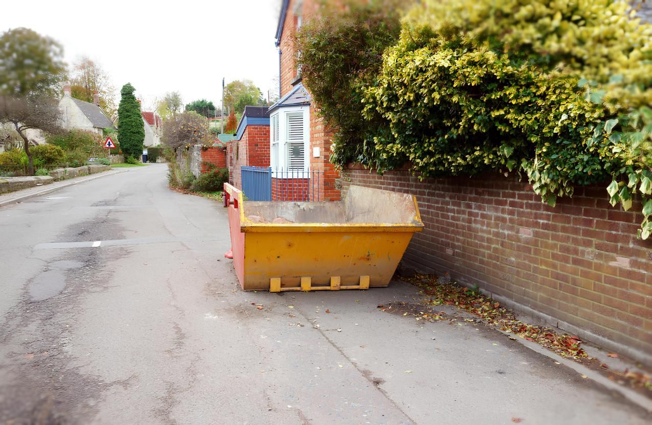 A Yellow Dumpster is Parked on the Side of the Road Next to a Brick Wall — IBS Skip Bins in Mapleton, QLD