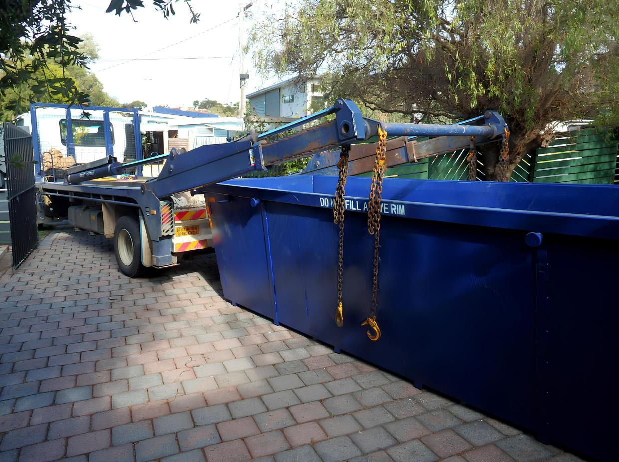A Blue Dumpster is Sitting on a Brick Sidewalk Next to a Truck — IBS Skip Bins in Mapleton, QLD