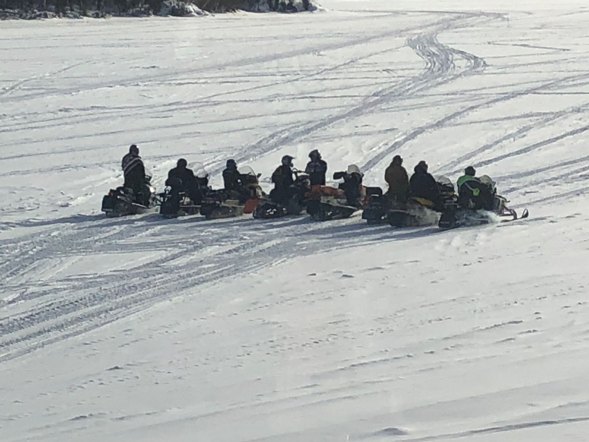 a group of people are riding snowmobiles in the snow .