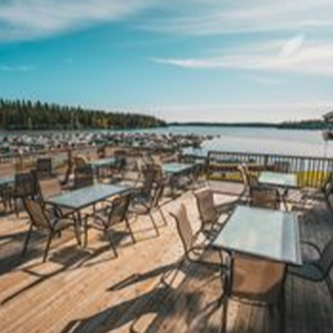 a wooden deck with tables and chairs overlooking a lake .
