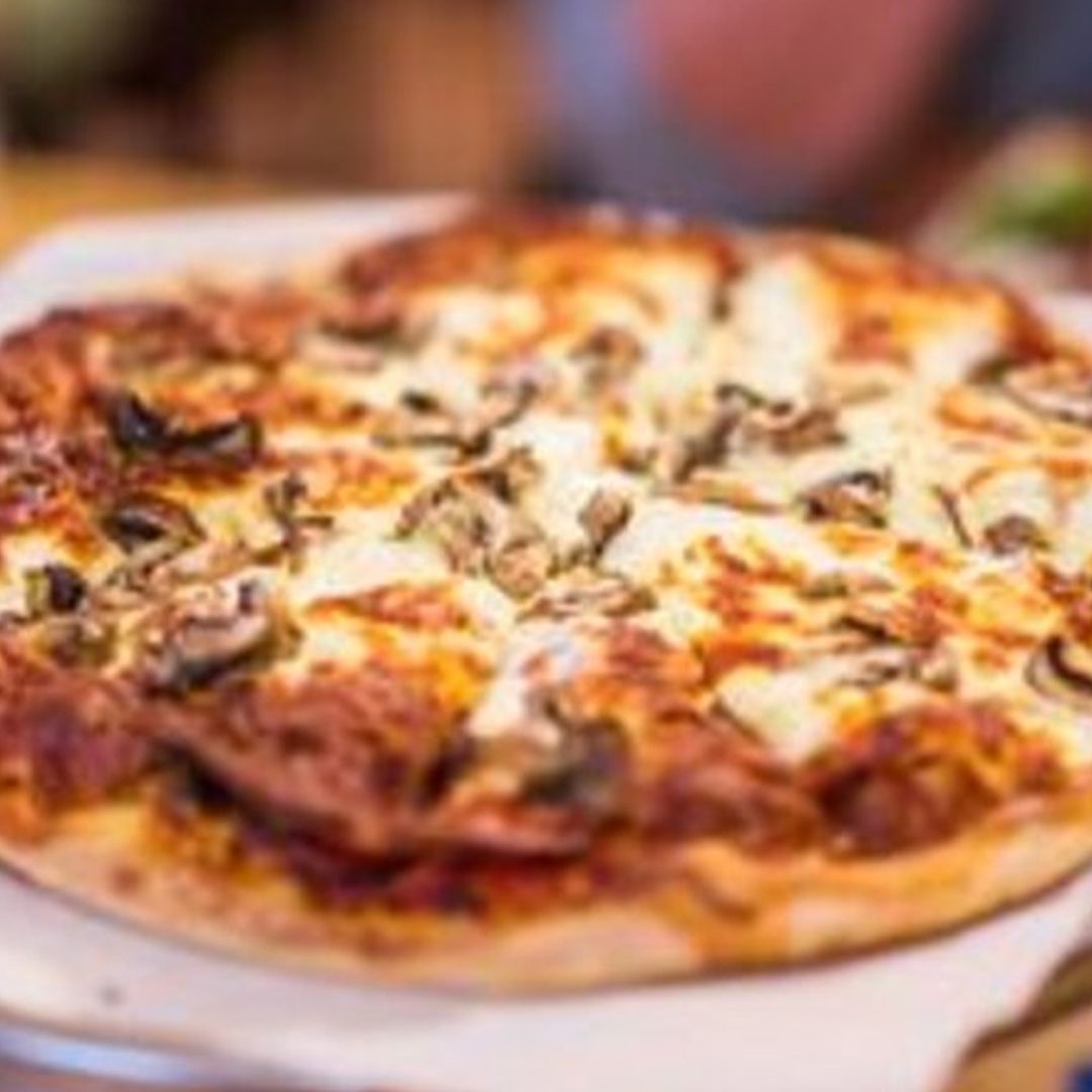 a pizza with mushrooms and cheese is sitting on a table .