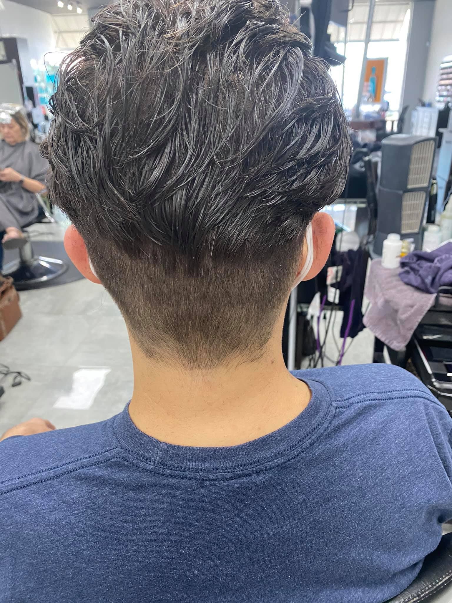 A man is getting his hair cut at a barber shop.