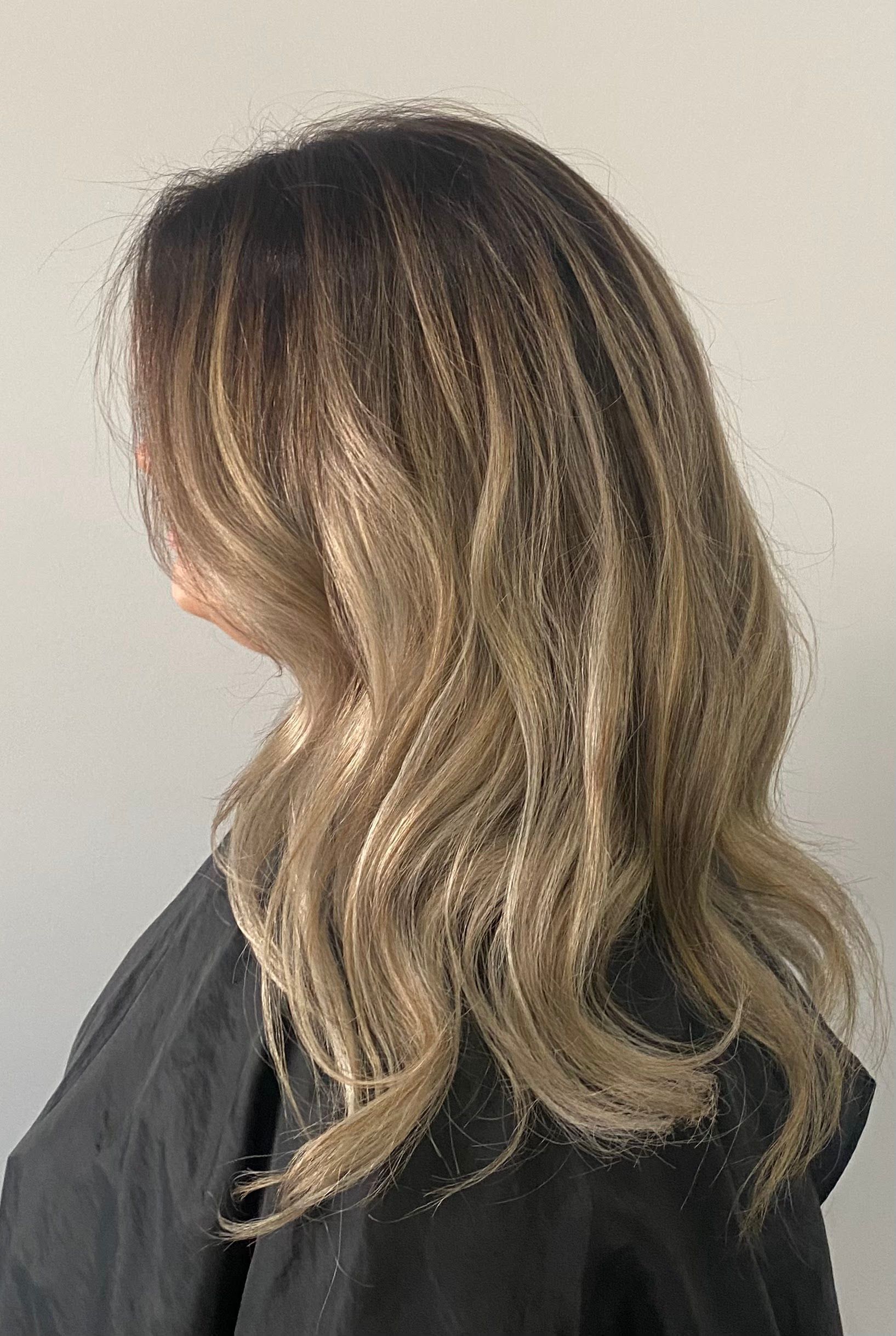 A woman with long blonde hair is wearing a black cape.