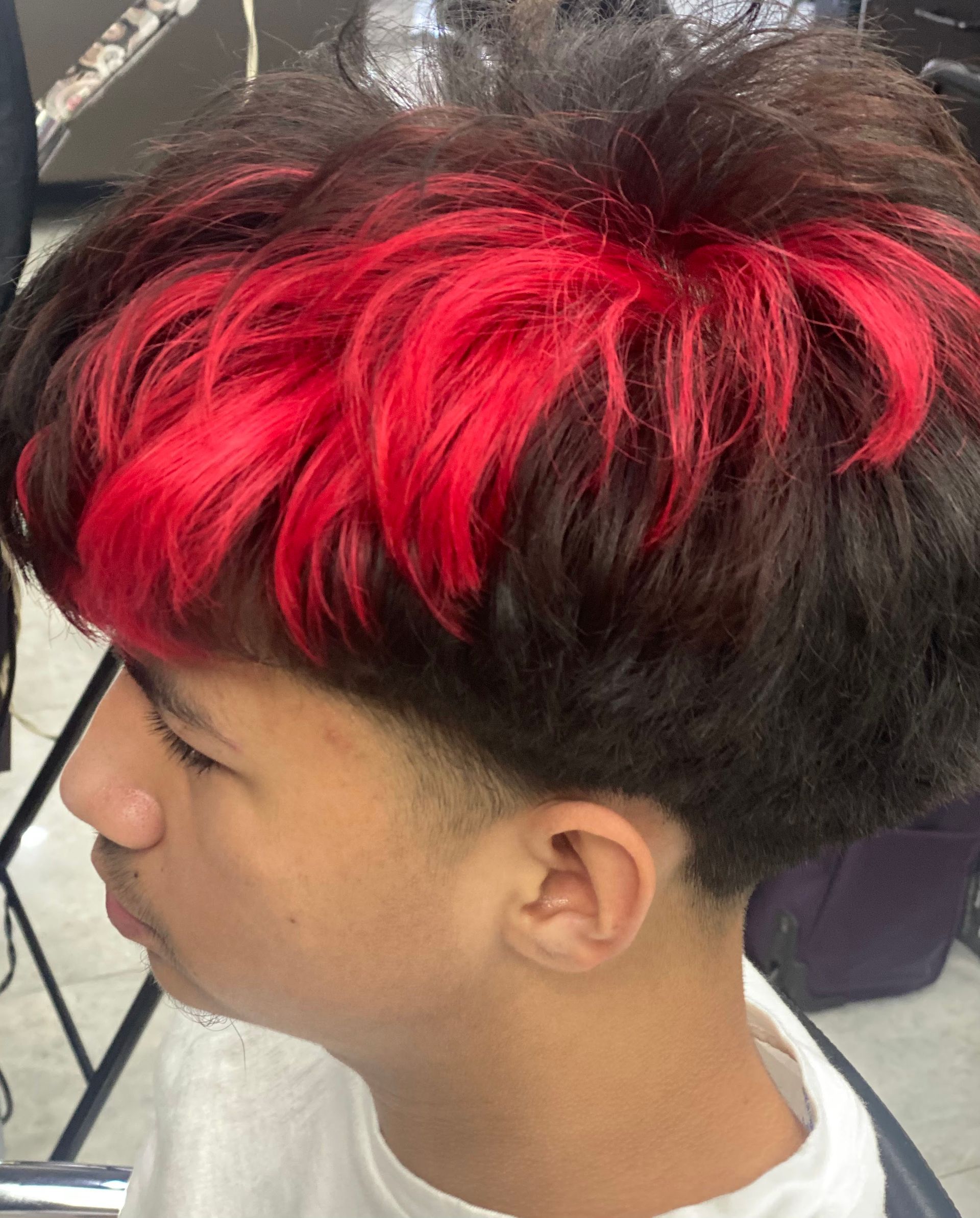 A young man with red hair is getting his hair cut.