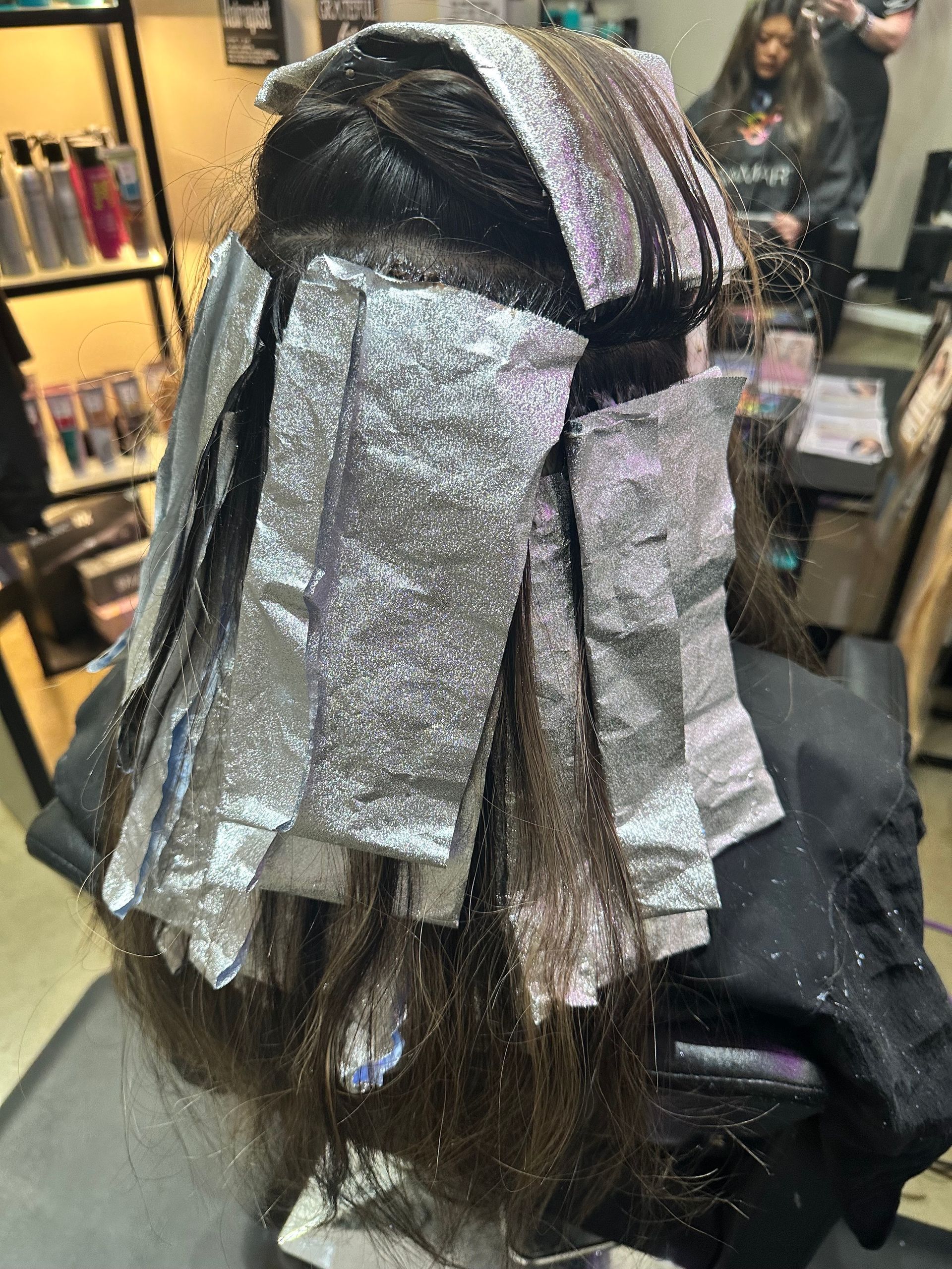 A woman is getting her hair dyed in a salon.