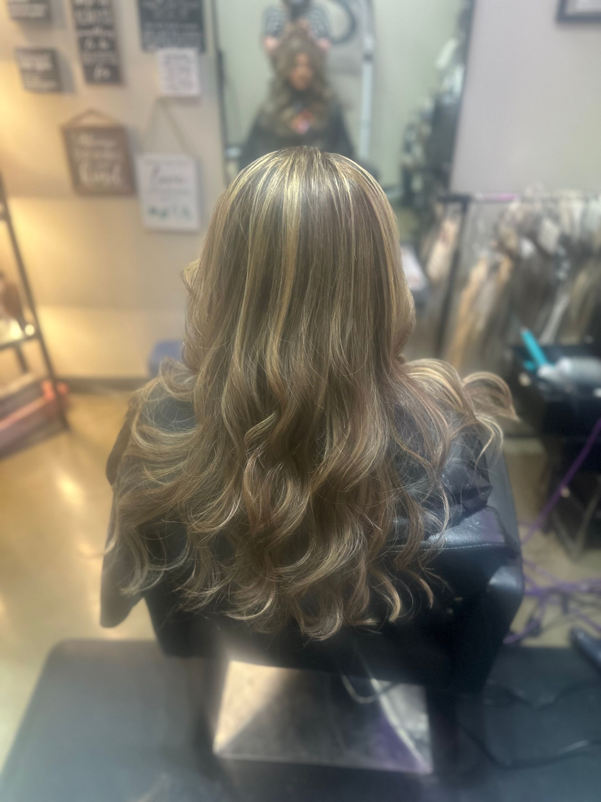 A woman is sitting in a chair with her hair in a salon.