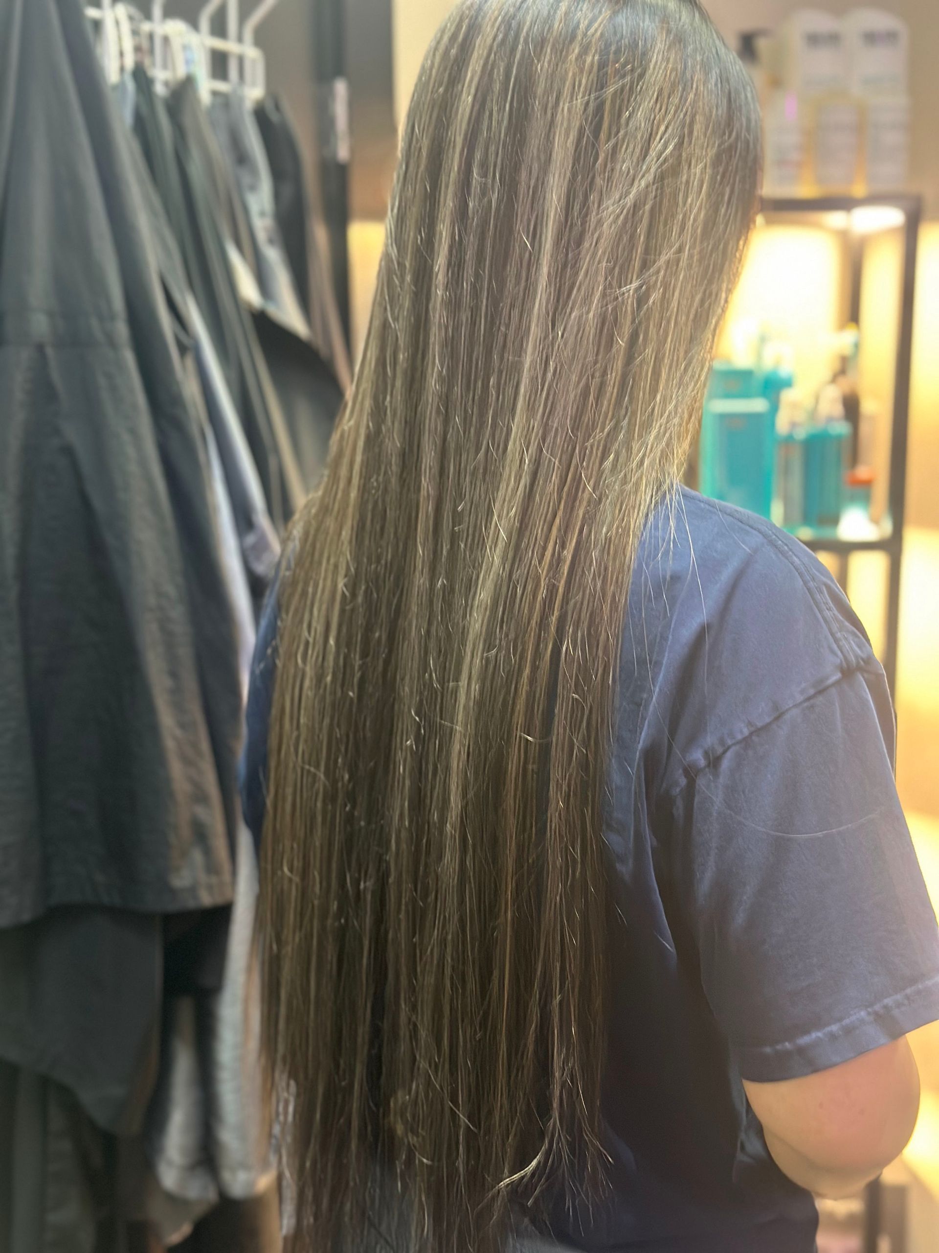 A woman with long hair is wearing a blue shirt and standing in a room.