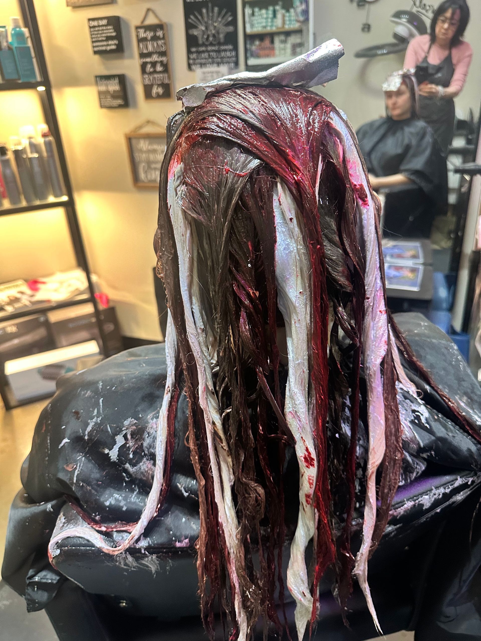 A woman is getting her hair dyed in a salon.