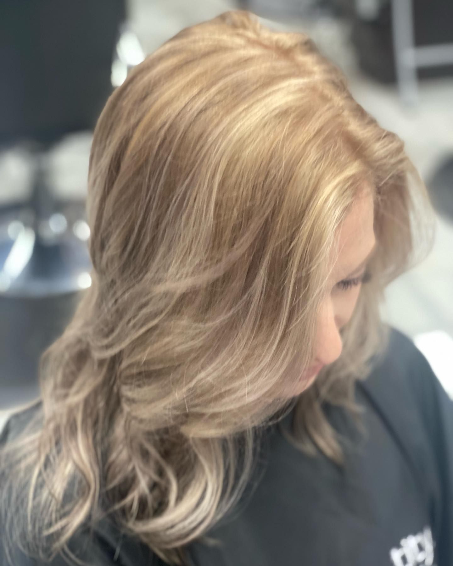 A woman with long blonde hair is wearing a black cape