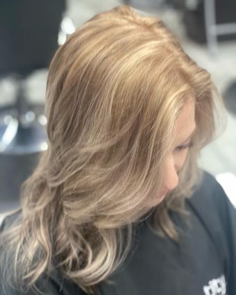 A woman with long blonde hair is wearing a black cape