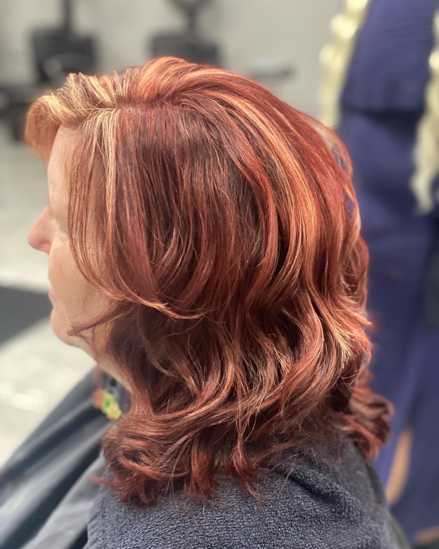 A woman with red hair is sitting in a chair.