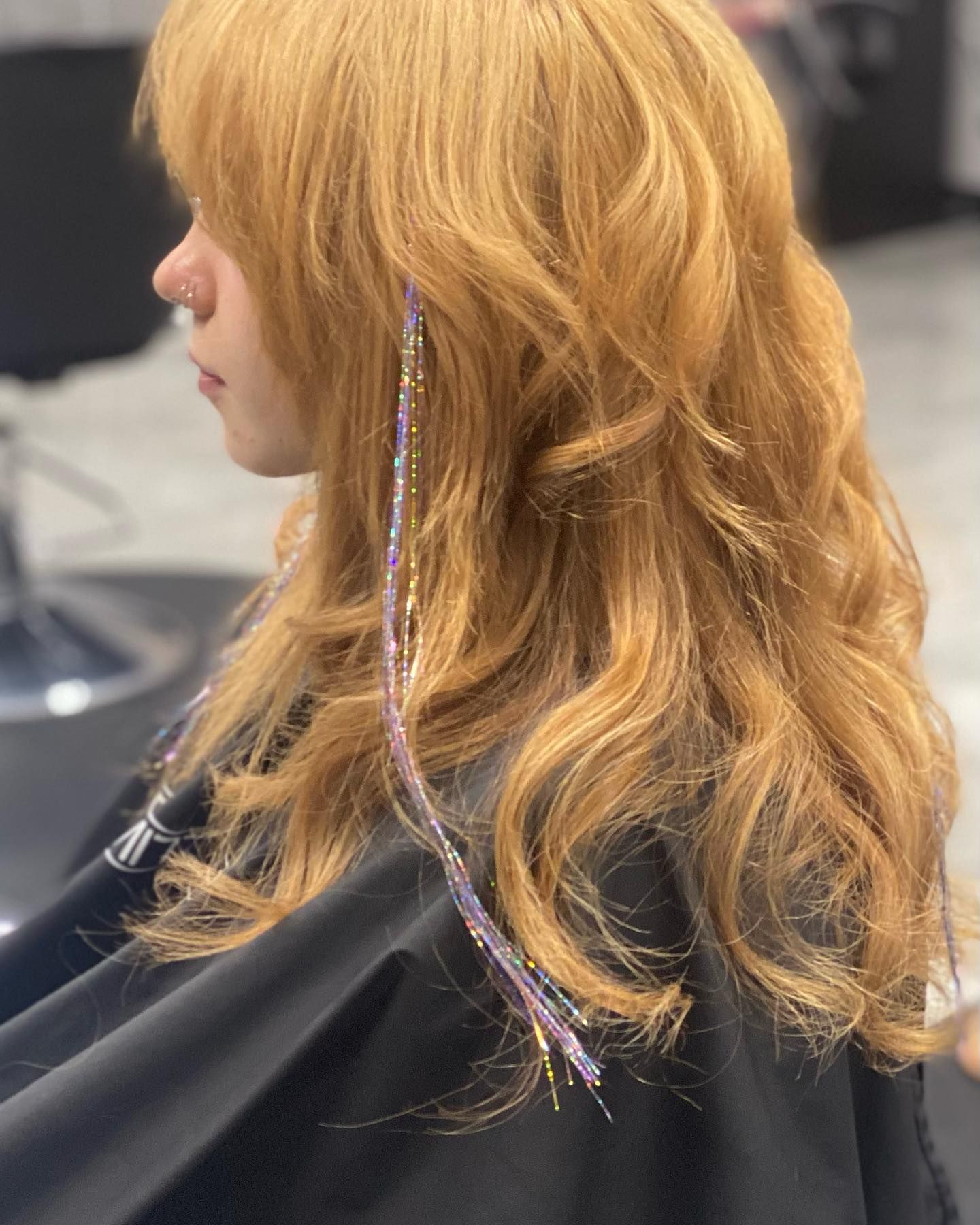 A woman with long blonde hair is sitting in a chair at a hair salon.