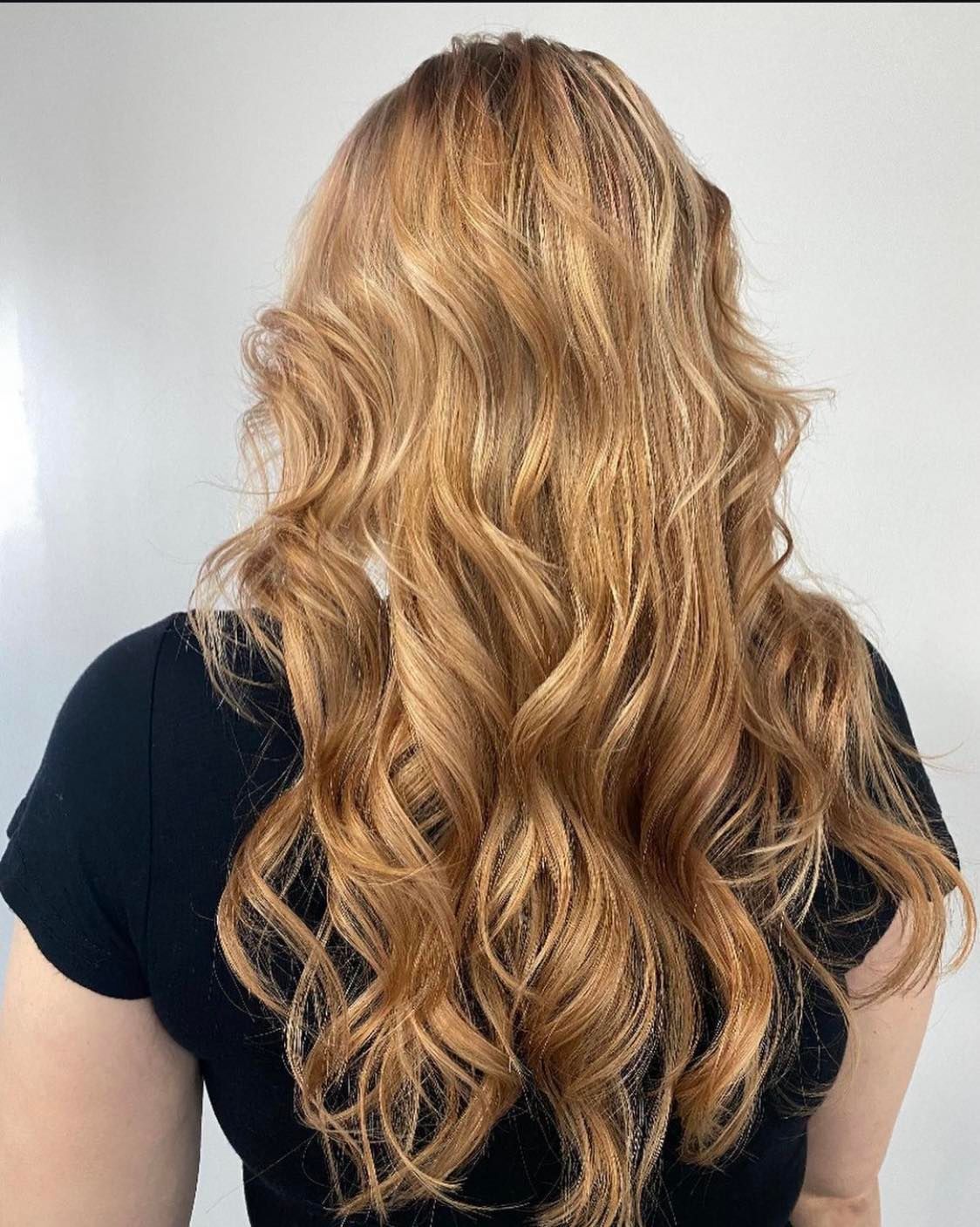 A woman with long wavy blonde hair is wearing a black shirt.