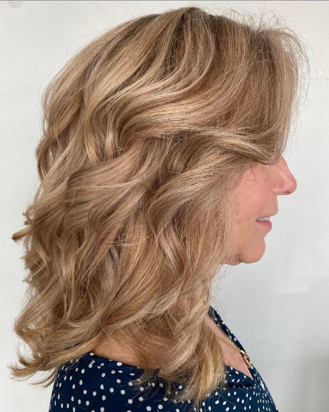 A woman with long blonde hair is wearing a blue polka dot shirt.