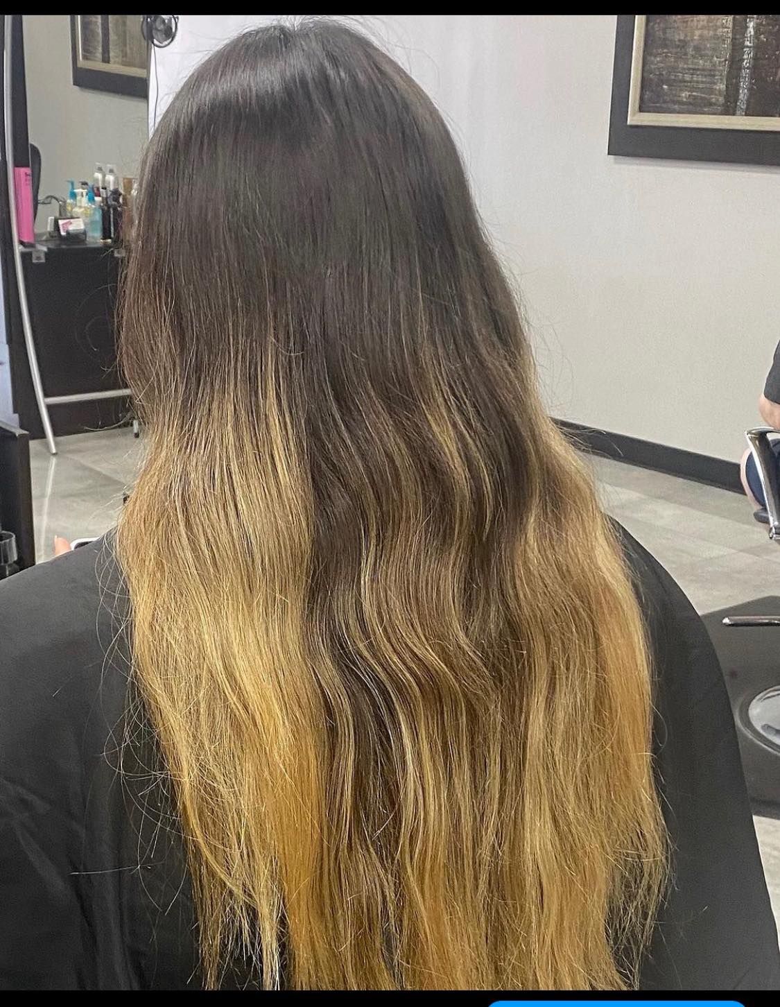 A woman with long hair is sitting in a chair in a salon.