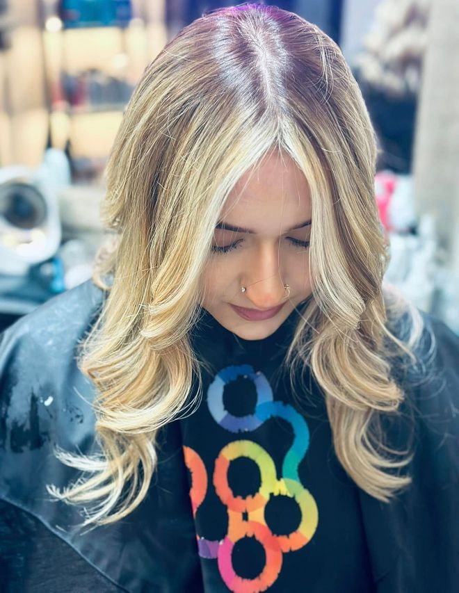 A woman with blonde hair is sitting in a chair with her eyes closed.