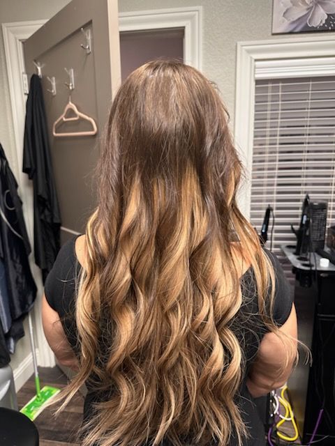 Long wavy brown hair with blonde highlights, viewed from behind in a bedroom.