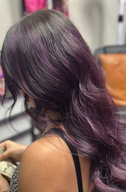 A woman with long purple hair is sitting in a chair.