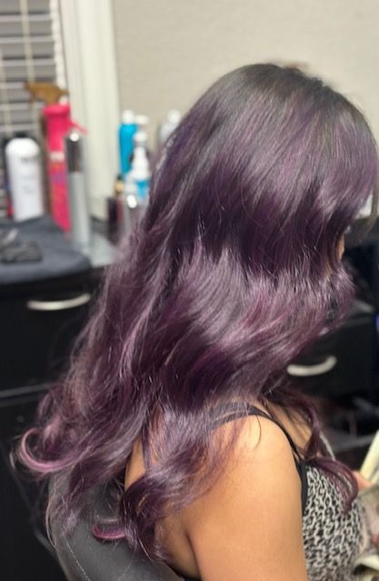 A woman with long purple hair is sitting in a chair.