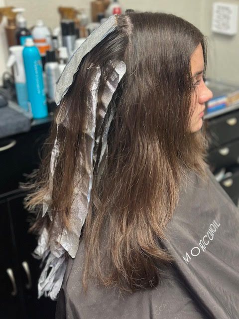 A woman is getting her hair dyed in a salon.