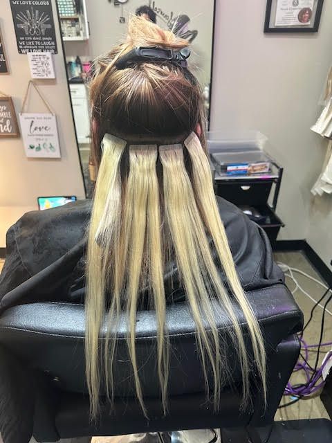 A woman with blue and purple hair is sitting in a chair in a salon.