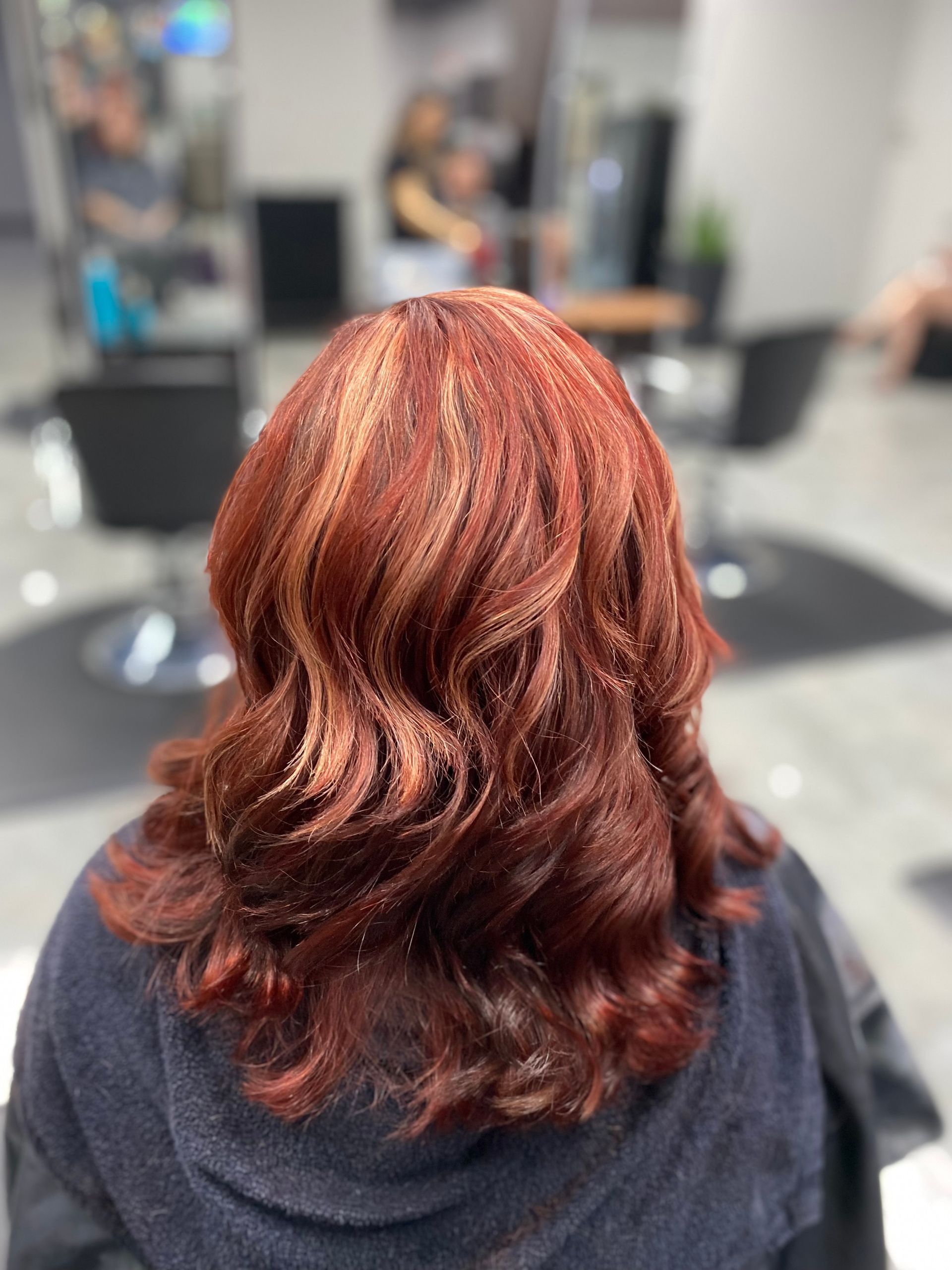 A woman with red hair is sitting in a chair in a salon.