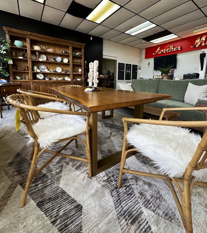 A wooden dining table with chairs featuring white faux-fur cushions, arranged in a furniture store showroom.