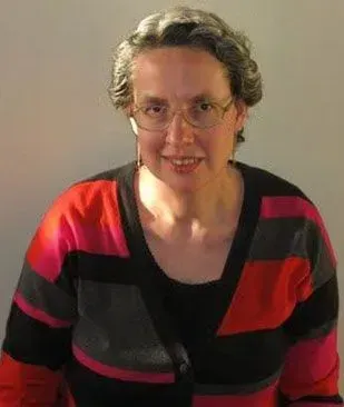 A woman wearing glasses and a striped sweater is smiling for the camera.