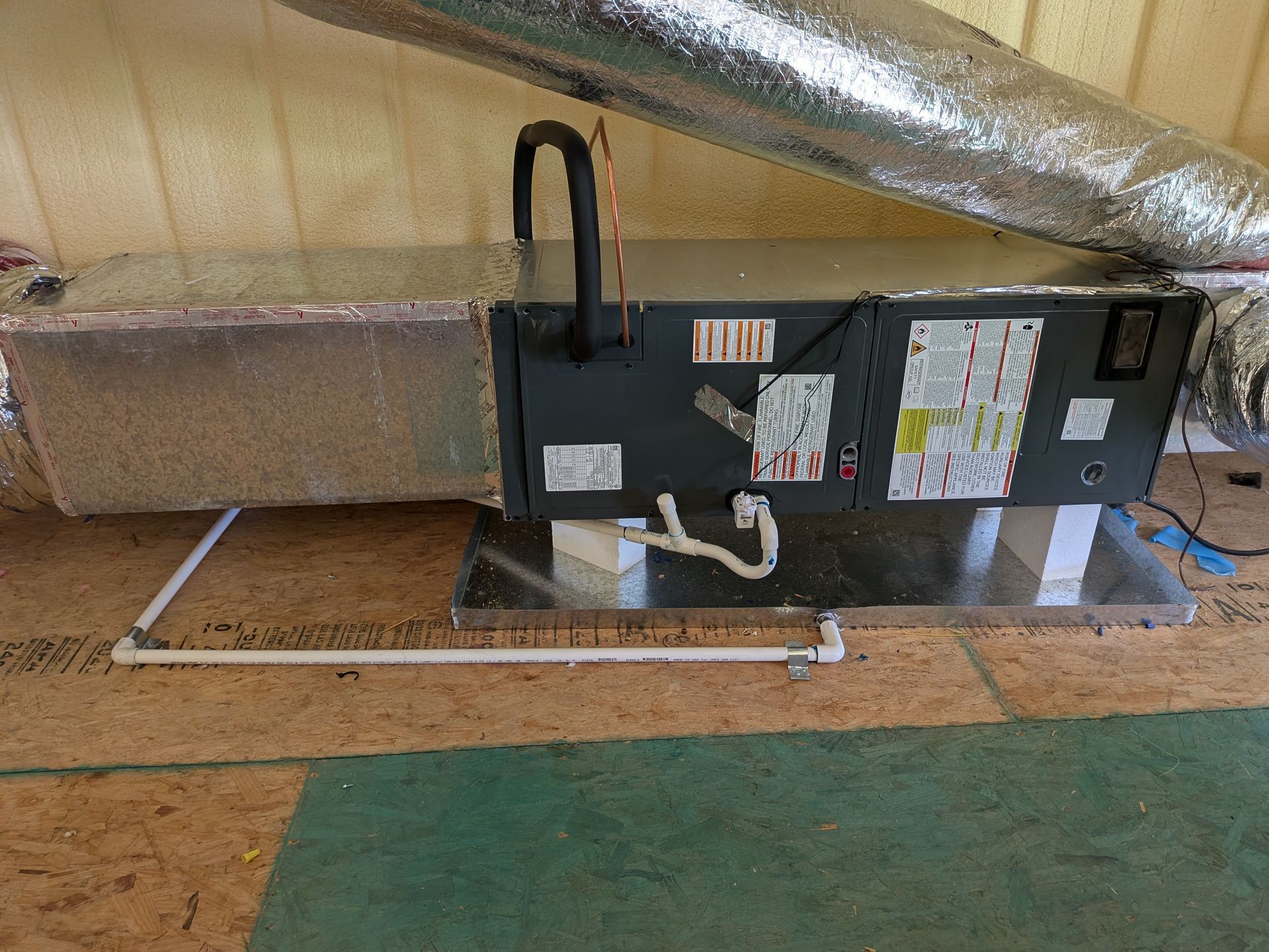 HVAC unit with ductwork, on a wooden floor. The unit is gray and silver.