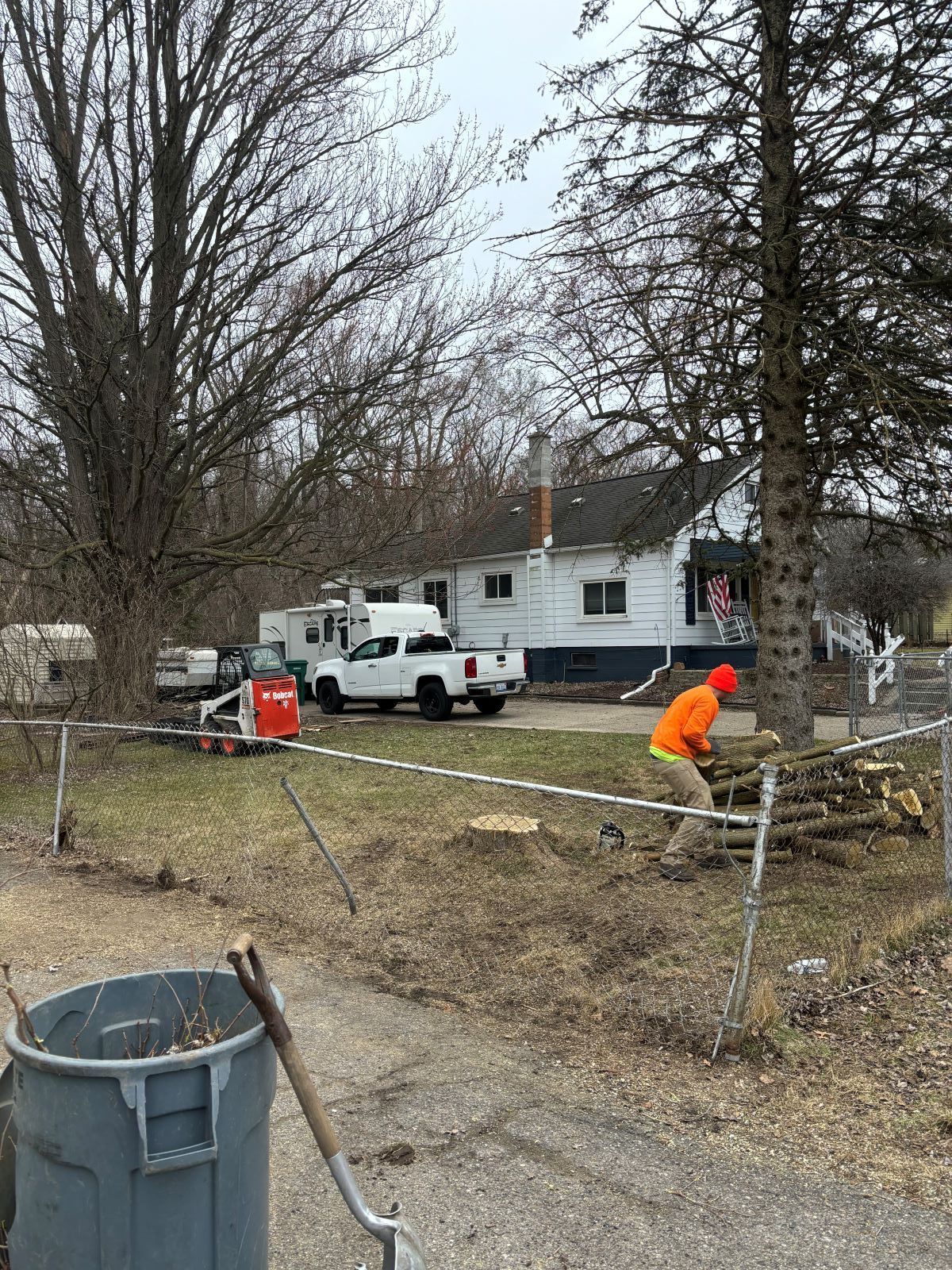 A man is cutting a tree in front of a house.