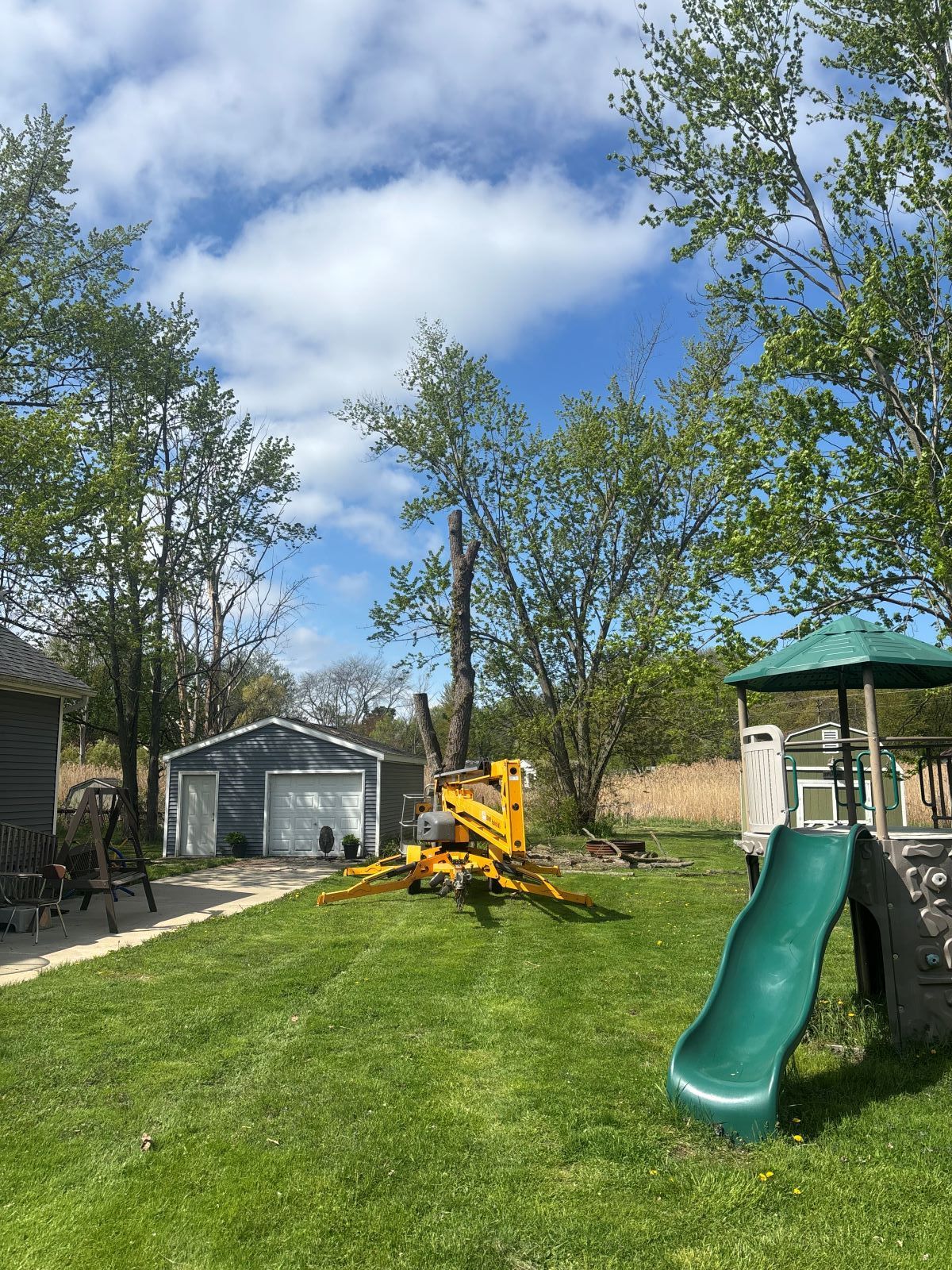 There is a green slide in the backyard of a house.