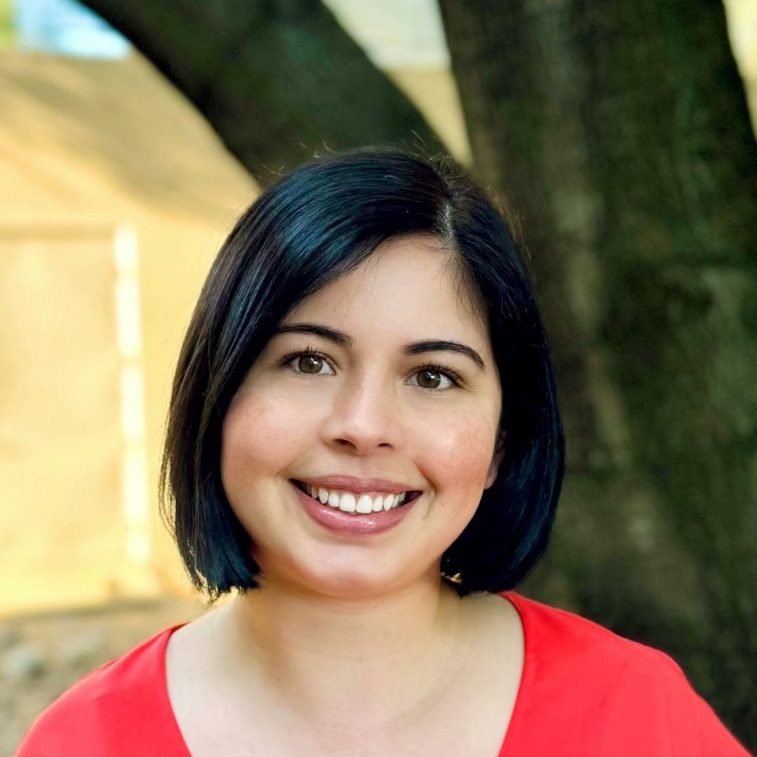 A woman in a red shirt smiles for the camera