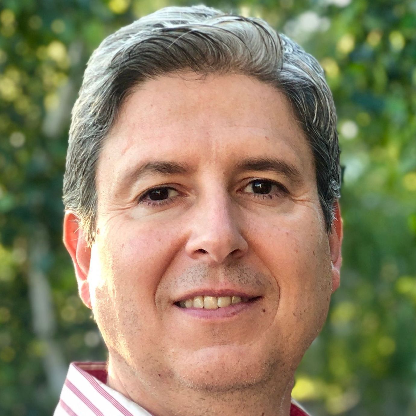 A close up of a man 's face with trees in the background