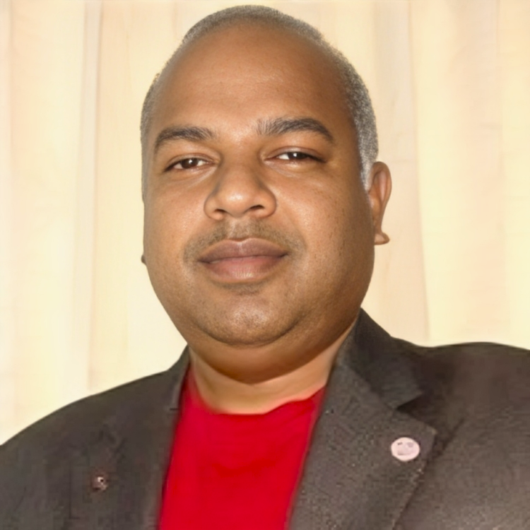 A man in a suit and red shirt is smiling for the camera