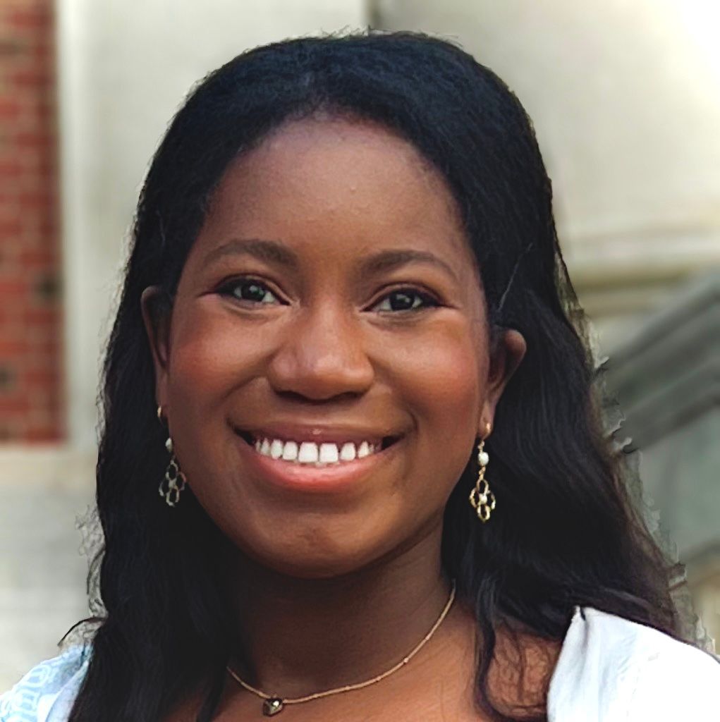 A woman wearing a necklace and earrings smiles for the camera