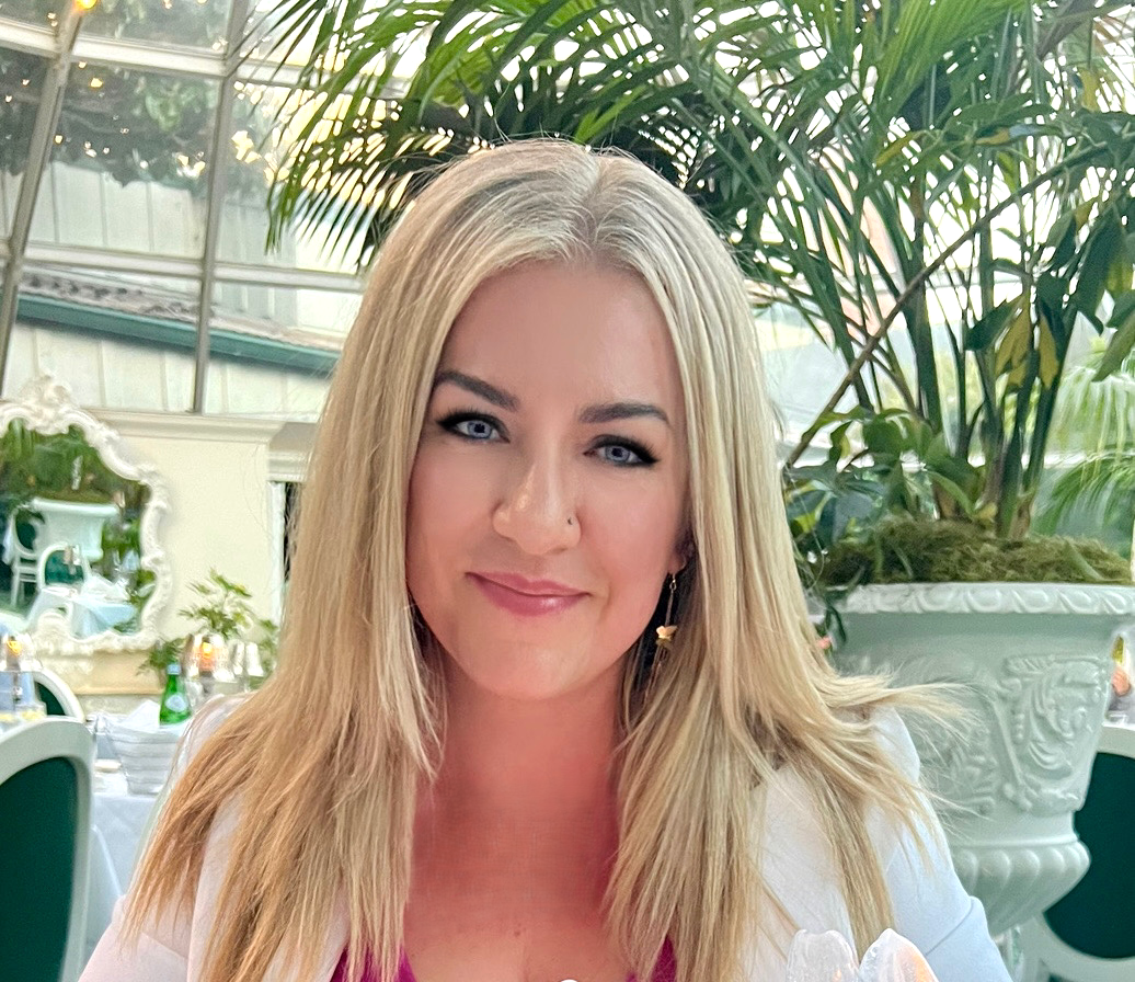 A woman is sitting at a table in front of a palm tree.