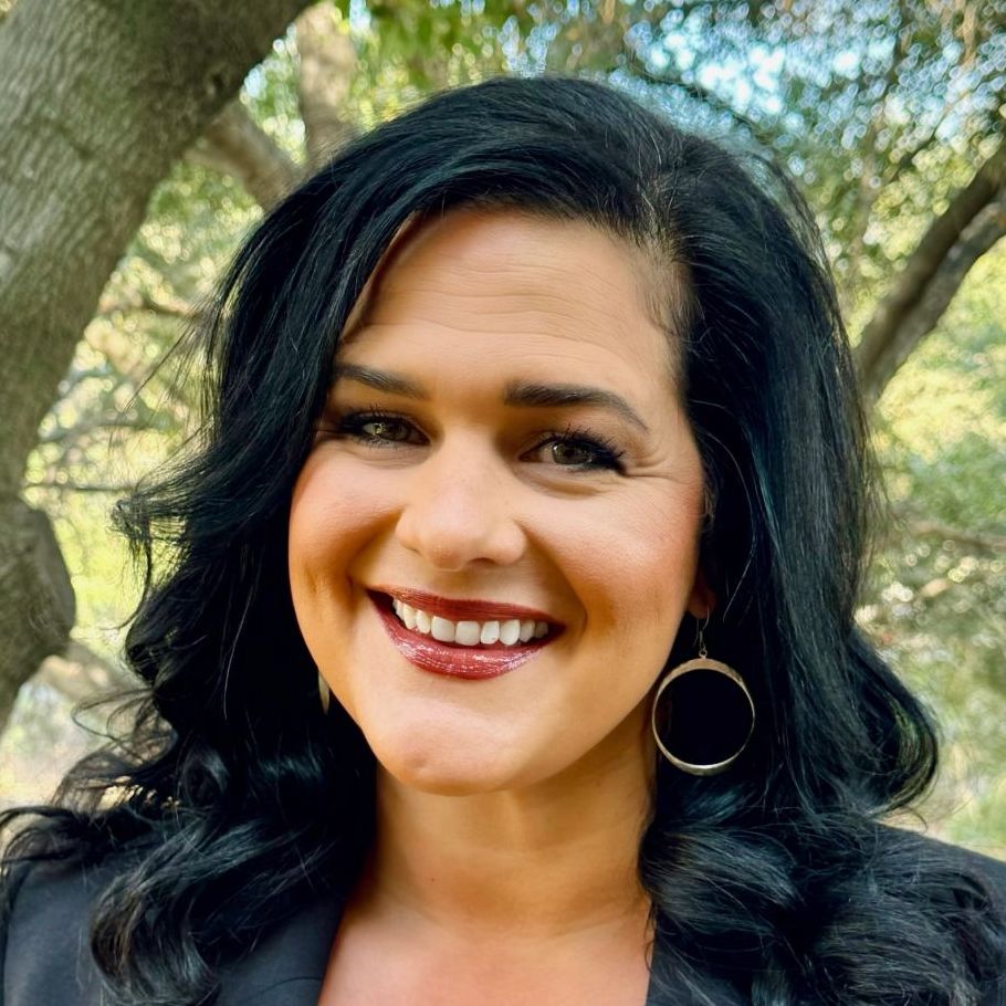 A woman with long black hair and hoop earrings is smiling for the camera.