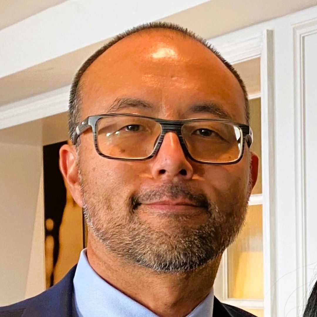 A man with glasses and a beard is wearing a suit and tie.