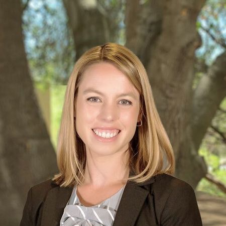 A woman in a suit and tie is smiling for the camera.