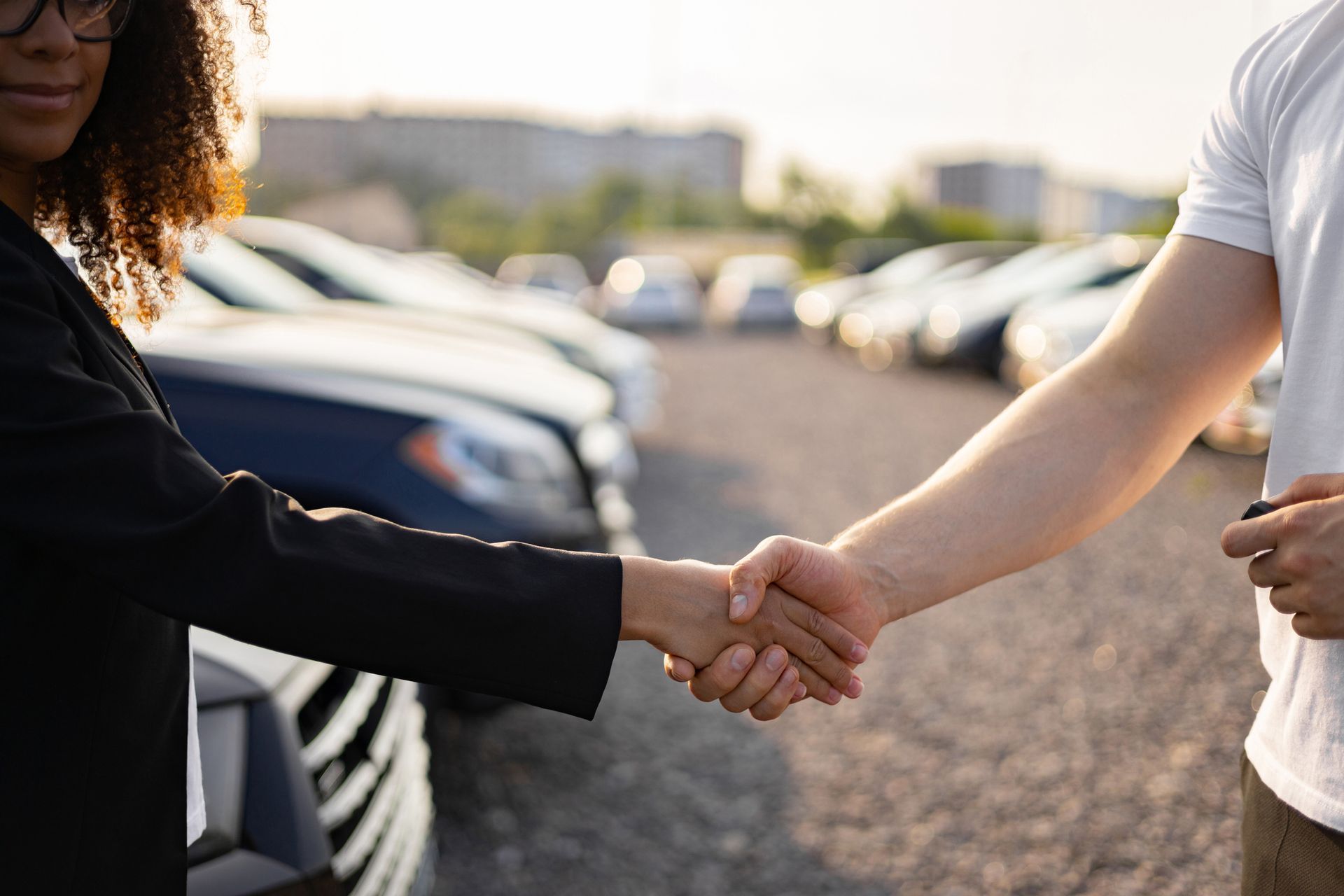 Una persona stringe la mano a un'altra davanti a un parcheggio.