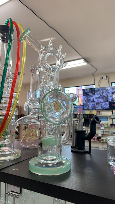 Glass water pipe with a green base and accents, on display at a store.