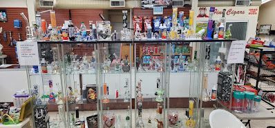 Interior shot of a smoke shop with glass pipes and bongs on display in glass cases.