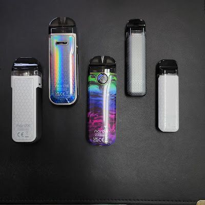 Five colorful vape devices on a black surface.